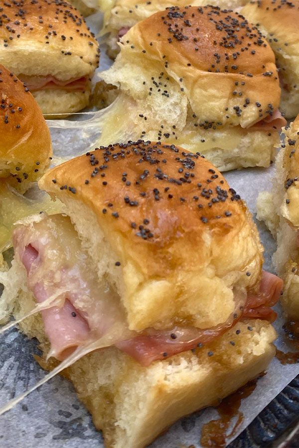 ham and cheese sliders with poppy seed sprinkles on a baking sheet