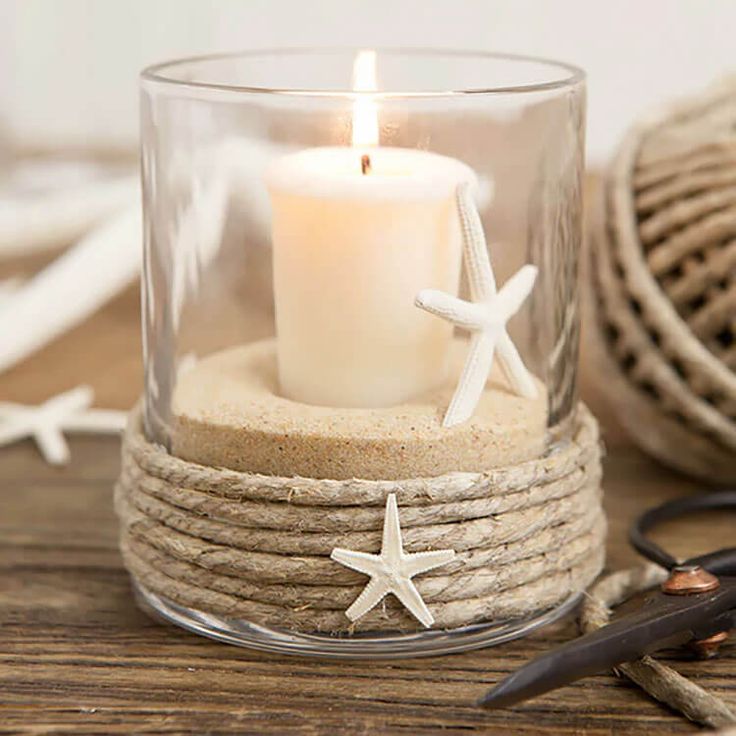 a candle that is sitting inside of a glass cup with rope and starfish on it