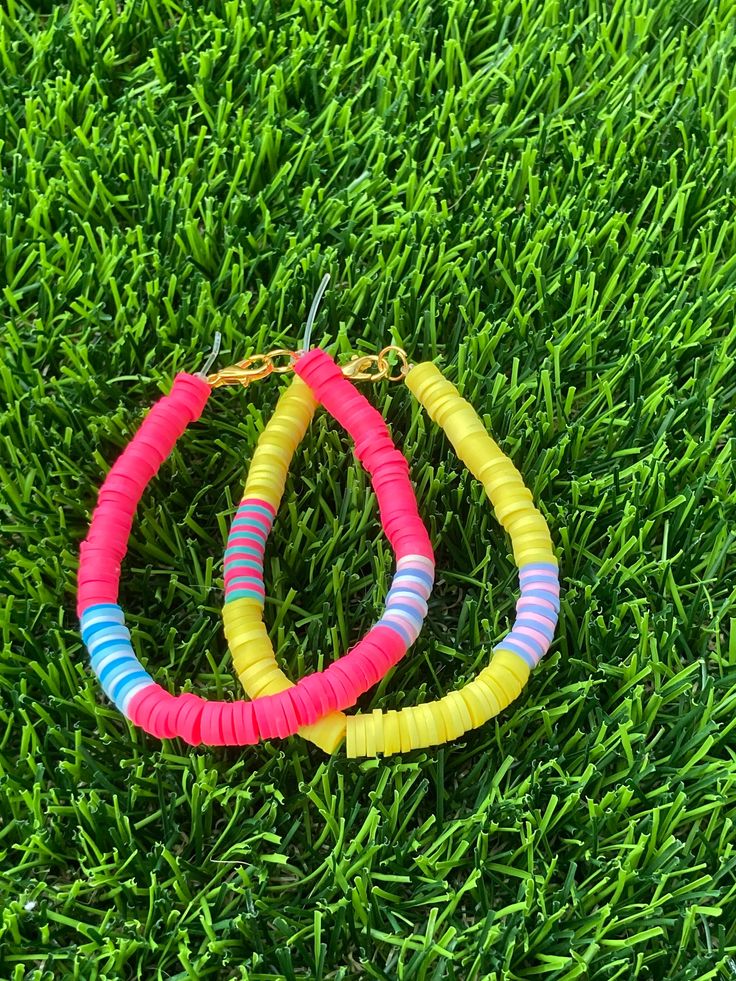 two colorful bracelets sitting on top of green grass