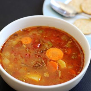 a white bowl filled with soup next to crackers on a black counter top,