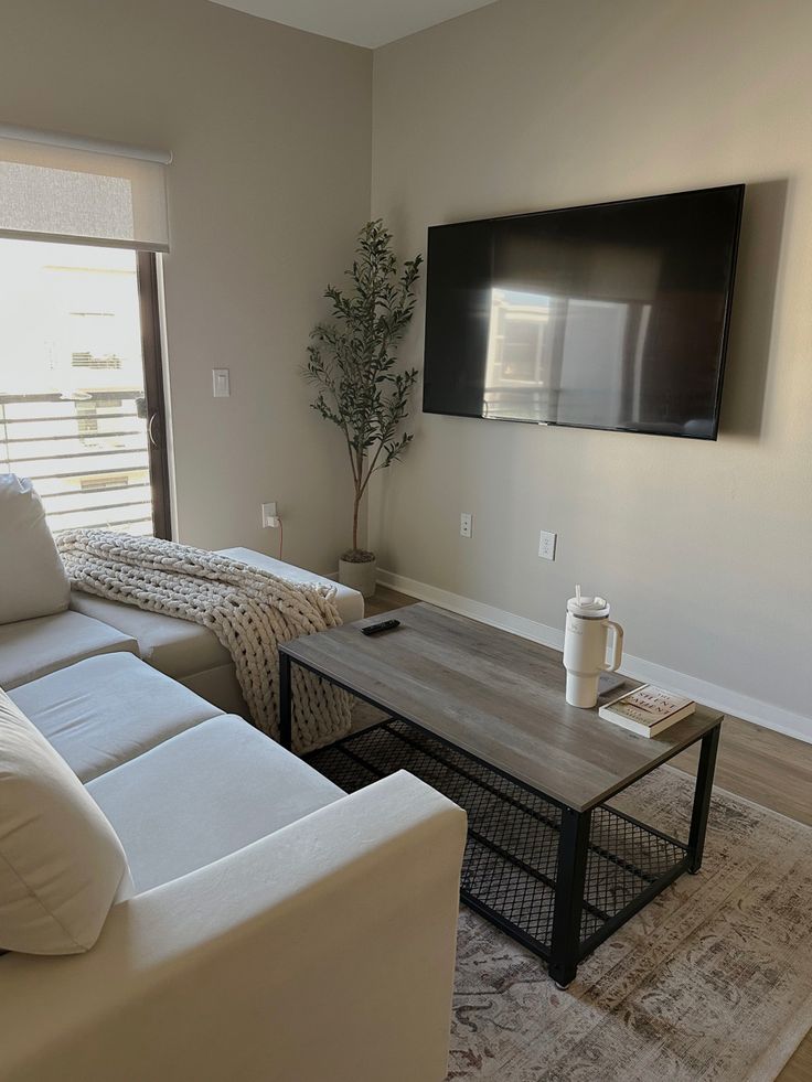 a living room with two couches and a coffee table in front of a flat screen tv