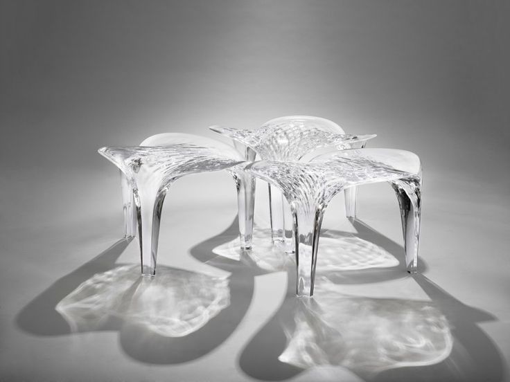 three clear chairs sitting next to each other on a white surface with shadows from them