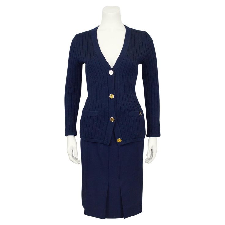 Classic and timeless Celine 100% wool navy blue cardigan and gabardine skirt ensemble from the 1970's. The set features a ribbed v neck cardigan with gold tone metal accents. Slit pockets at the hips with beige embroidered logo on the left hip and large gold tone metal buttons. The pleated skirt is high waisted with a half navy blue leather and gold horse bit belt like detail at waistband. Inverted top stitched pleats on the front and back. Overall A line shape. Side back zipper with hook and ey Navy Blue Cardigan, Gold Horse, Stretch Skirt, Blue Cardigan, Metal Accents, V Neck Cardigan, Blue Wool, Wool Cardigan, Metal Buttons