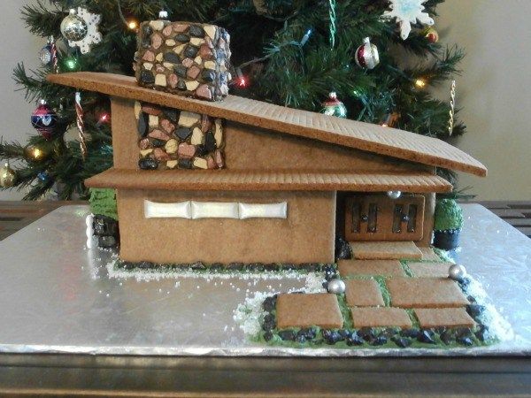 a gingerbread house is on display in front of a christmas tree