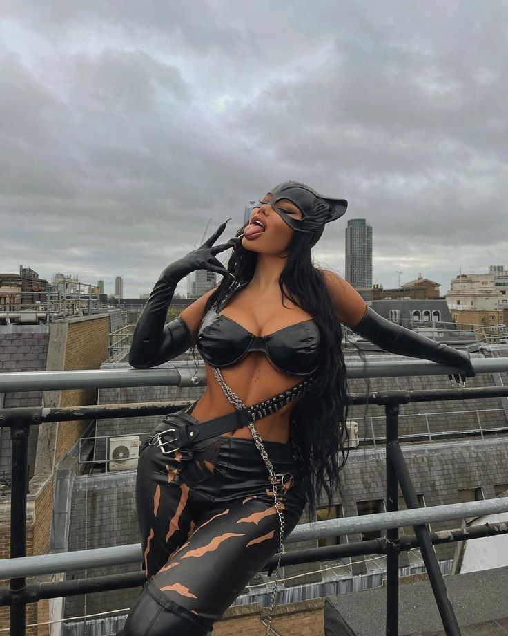 a woman in leather clothes posing on top of a building