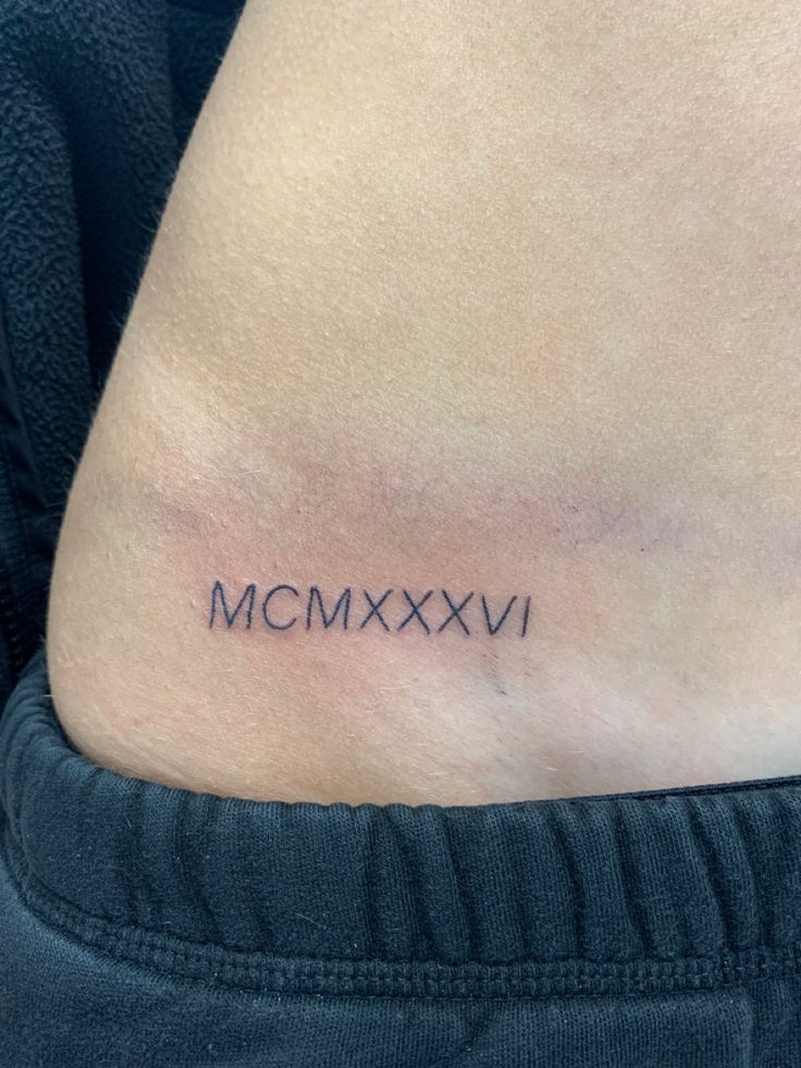 a woman's stomach with the word mcmxxvi tattooed on her lower back