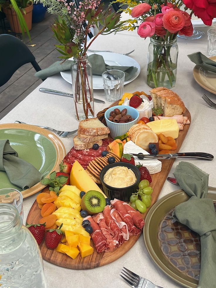 a table topped with plates and bowls filled with food next to vases full of flowers