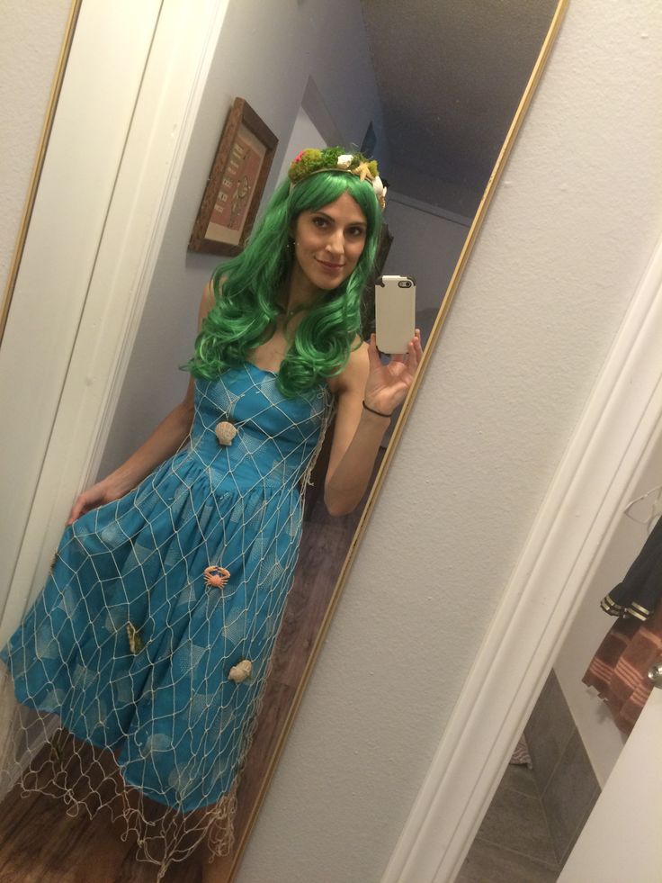 a woman with green hair taking a selfie in a mirror wearing a blue dress