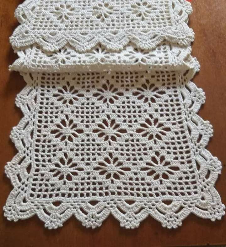 two pieces of white crocheted doily sitting on top of a wooden table