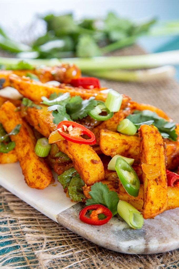 some type of food on a white plate with green onions and red peppers in the background