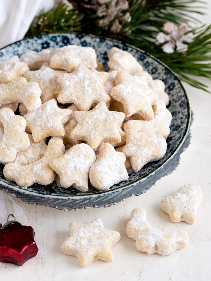 a bowl full of snowflake cookies next to christmas decorations