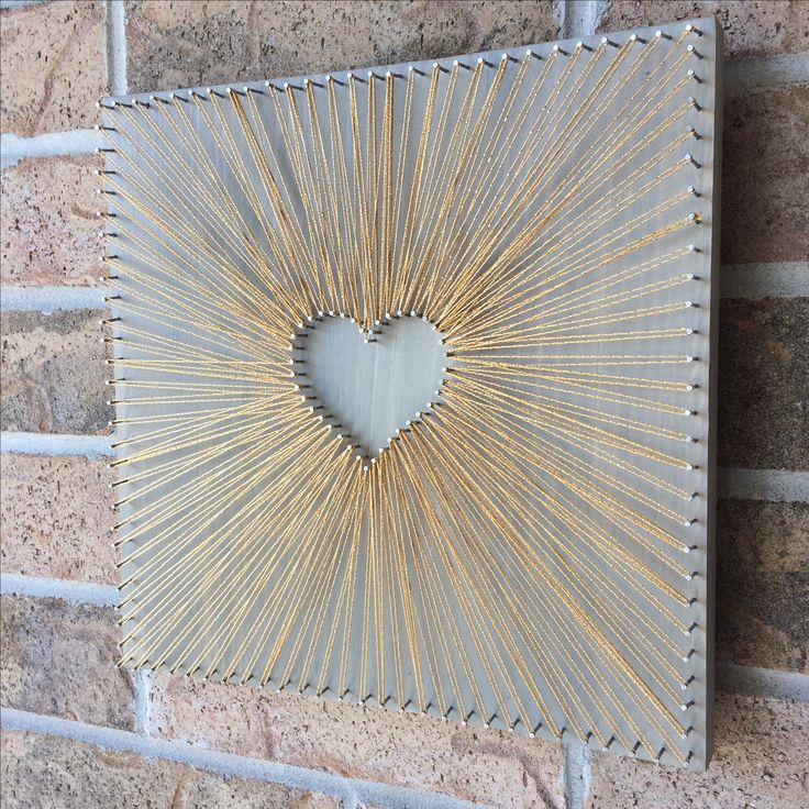 a heart shaped metal frame hanging on a brick wall