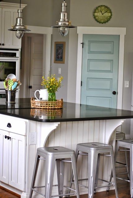 a kitchen island with stools in front of it and a clock on the wall