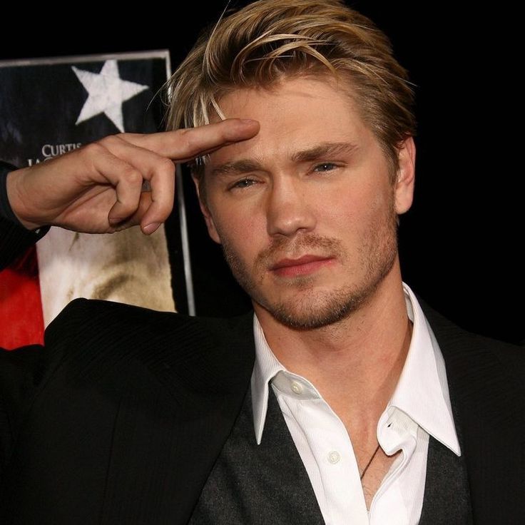 a man in a black suit and white shirt is holding his hand up to his forehead