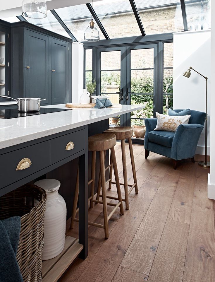 a kitchen with an island, stools and glass doors leading to the back patio