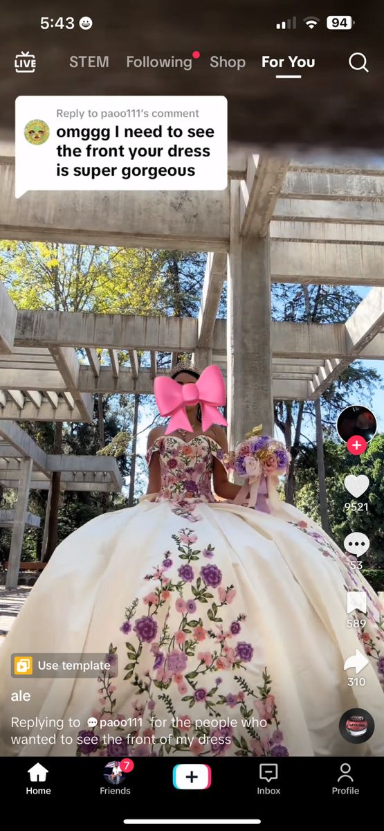 a woman in a white dress with pink bows on her head is standing under a wooden structure