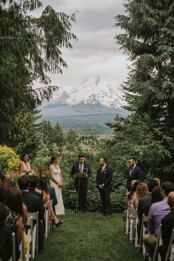 a bride and groom standing at the end of their wedding ceremony in front of a mountain