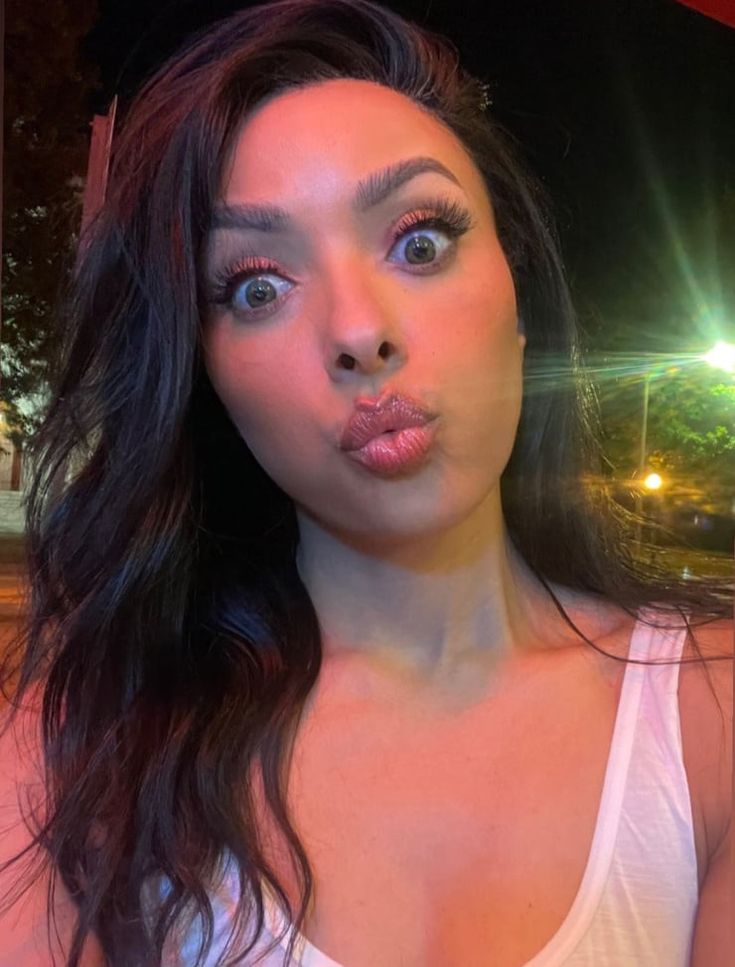 a woman making a funny face with her tongue sticking out to the side while wearing a white tank top