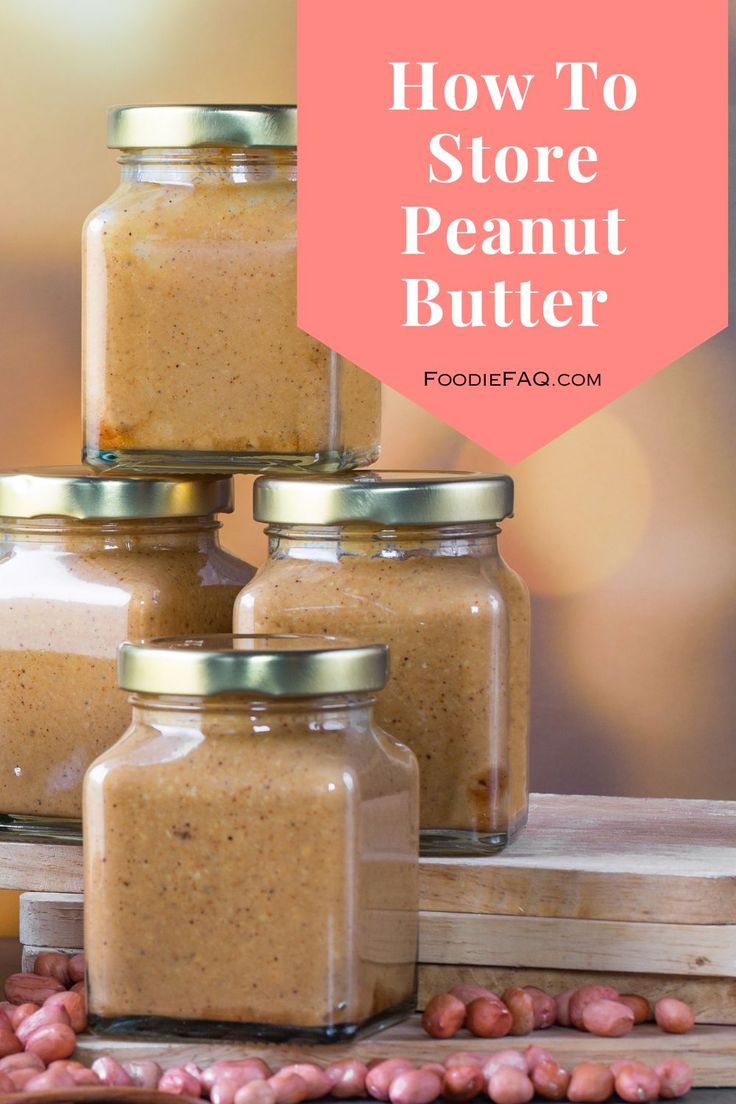 three jars filled with peanut butter sitting on top of a wooden table next to peanuts