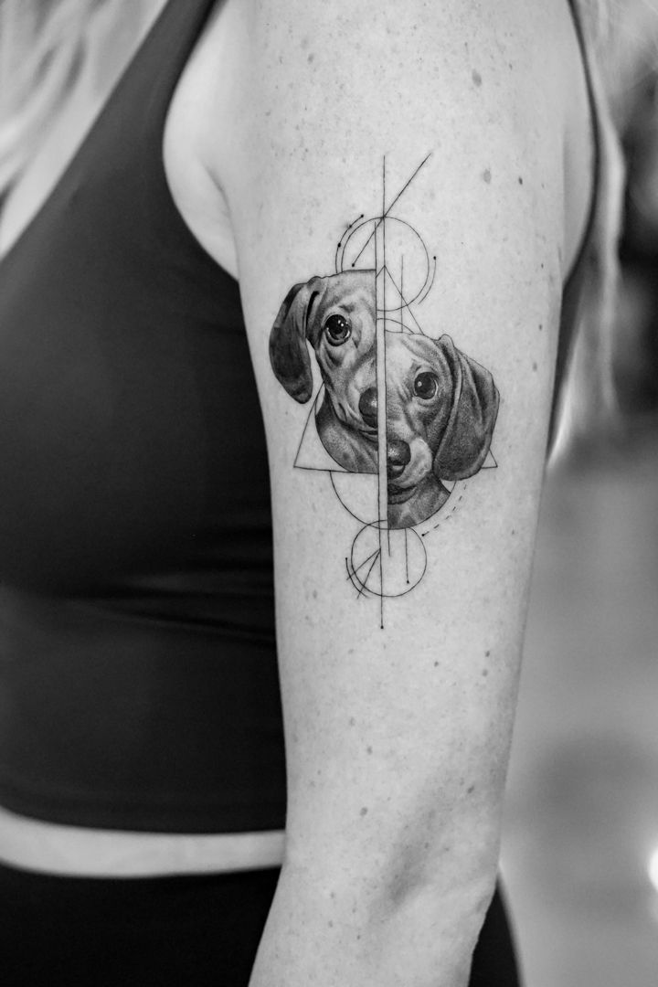 a woman's arm with a dog on it and a geometric triangle behind her