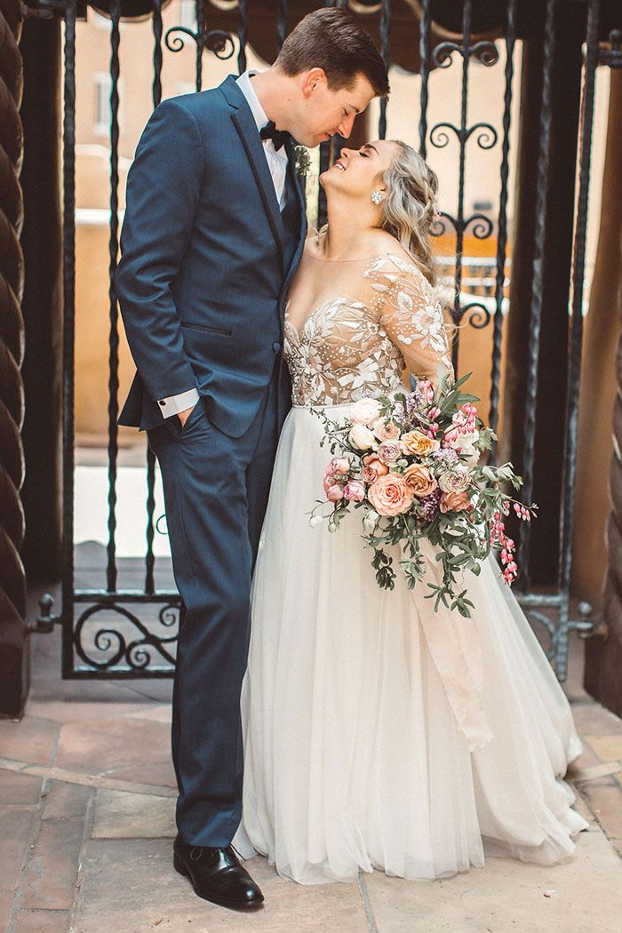 a bride and groom kissing in front of an iron gate