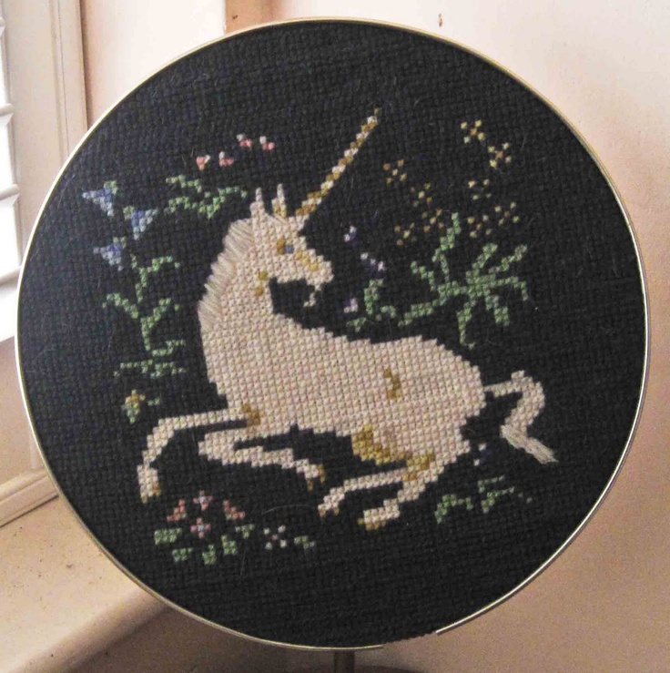 a cross - stitch picture of a unicorn on a black background with flowers and leaves