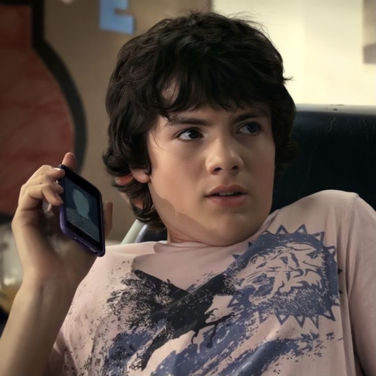 a young boy holding up a cell phone