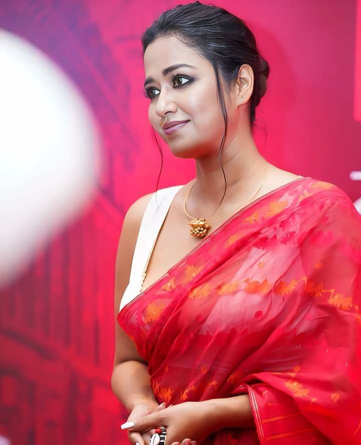 a woman in a red sari holding a cell phone and smiling at the camera