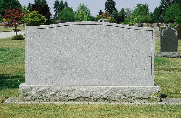 a headstone in the middle of a cemetery with trees in the background and grass on both sides