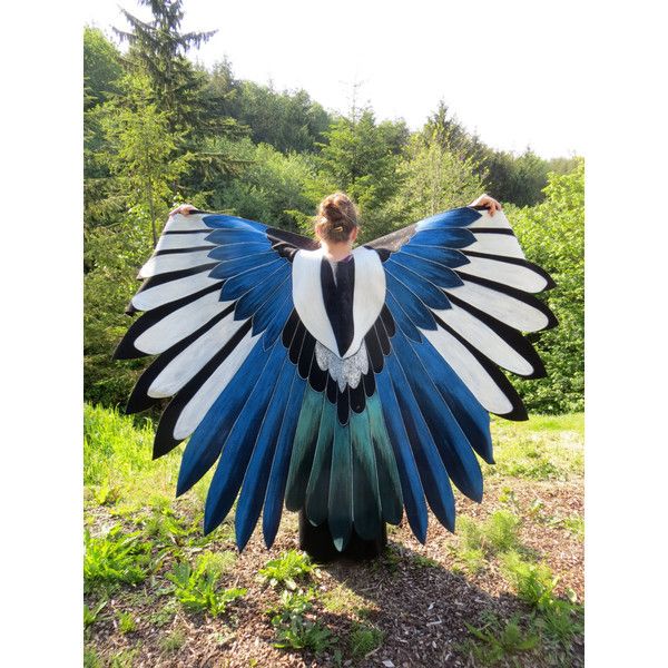 a woman standing in the grass with her wings spread open