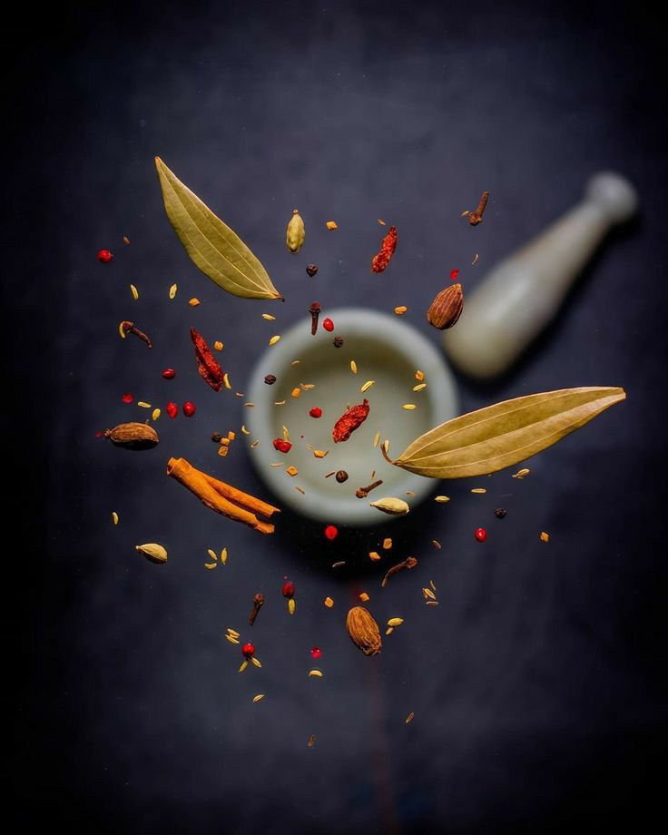 an assortment of spices and herbs in a mortar bowl on a dark background with space for text