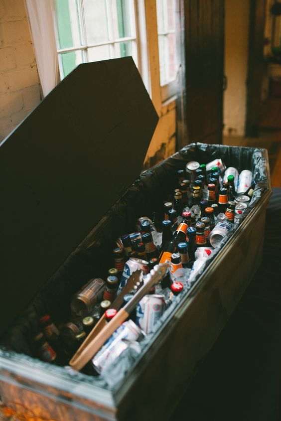 an open box filled with lots of beer bottles and cans in front of a window