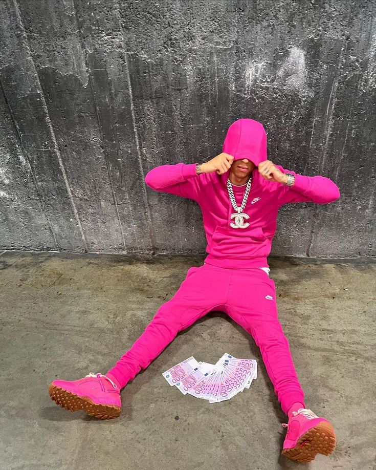 a person in a pink outfit laying on the ground with their hands behind their head