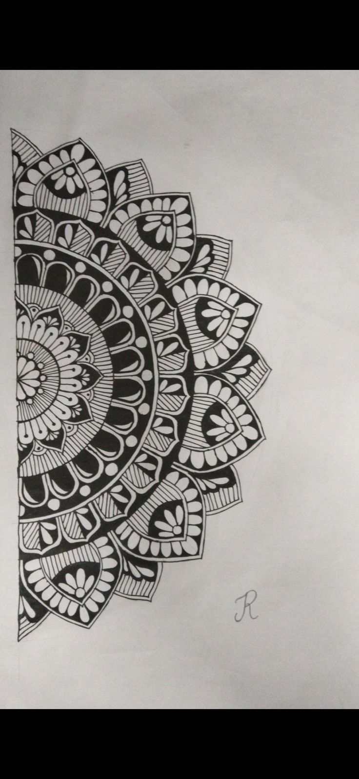 a drawing of a black and white flower on paper with the letter s in it