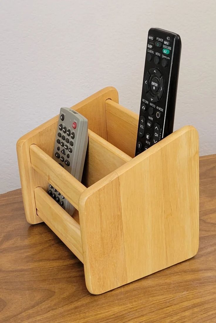 two remote controls in a wooden holder on a table