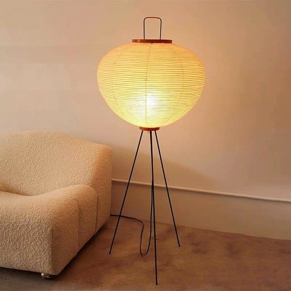 a floor lamp sitting on top of a wooden tripod next to a white chair