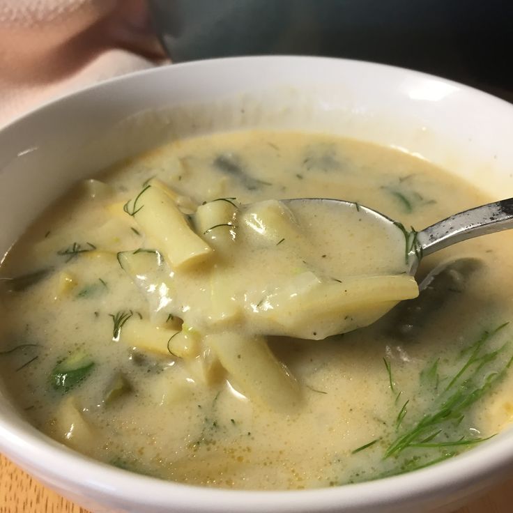 a white bowl filled with soup on top of a wooden table