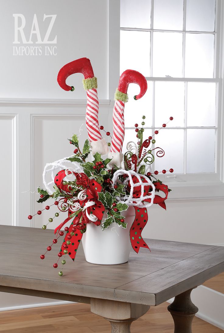 a christmas centerpiece with candy canes and greenery in a white vase on a wooden table