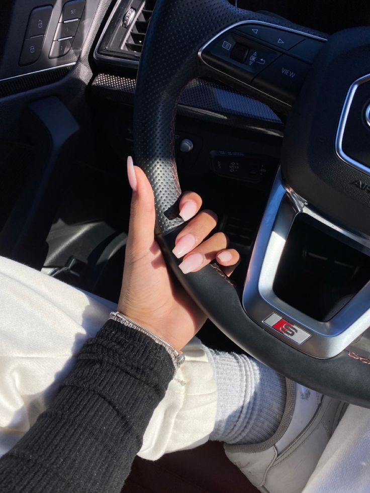 a woman is holding the steering wheel of a car with her hand on the steering wheel