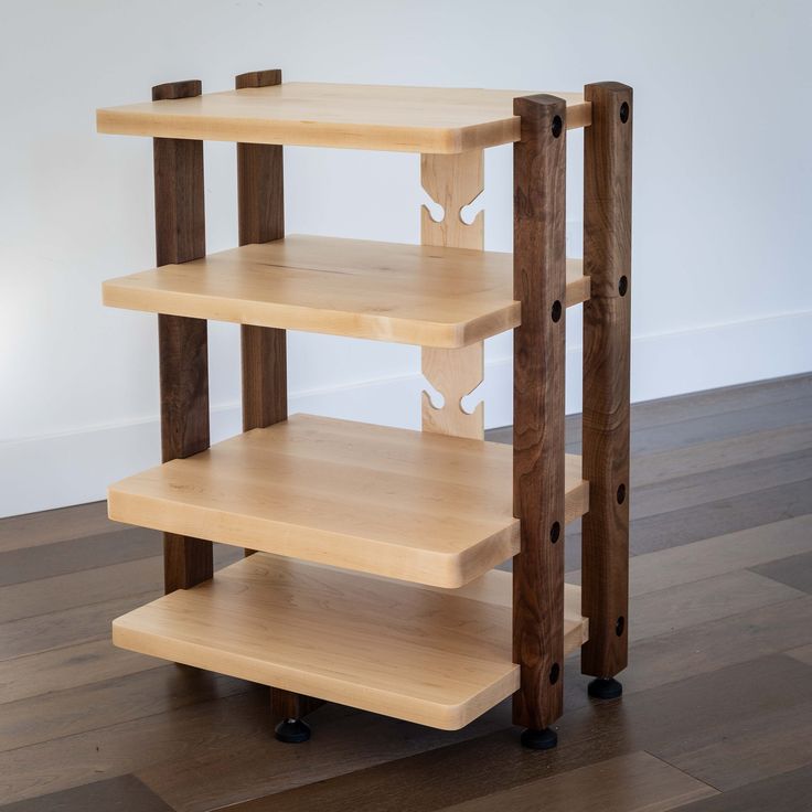 three wooden shelves on wheels in an empty room with hard wood flooring and white walls