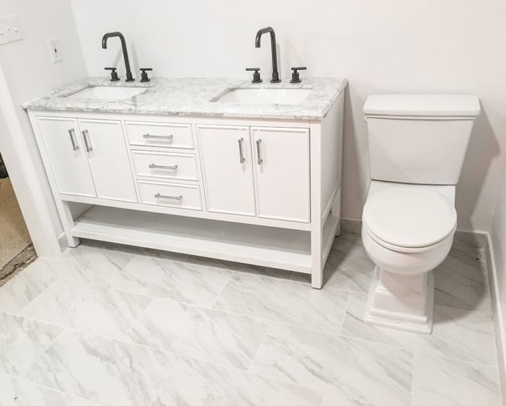 two sinks and a toilet in a bathroom with white walls, marble floors and flooring