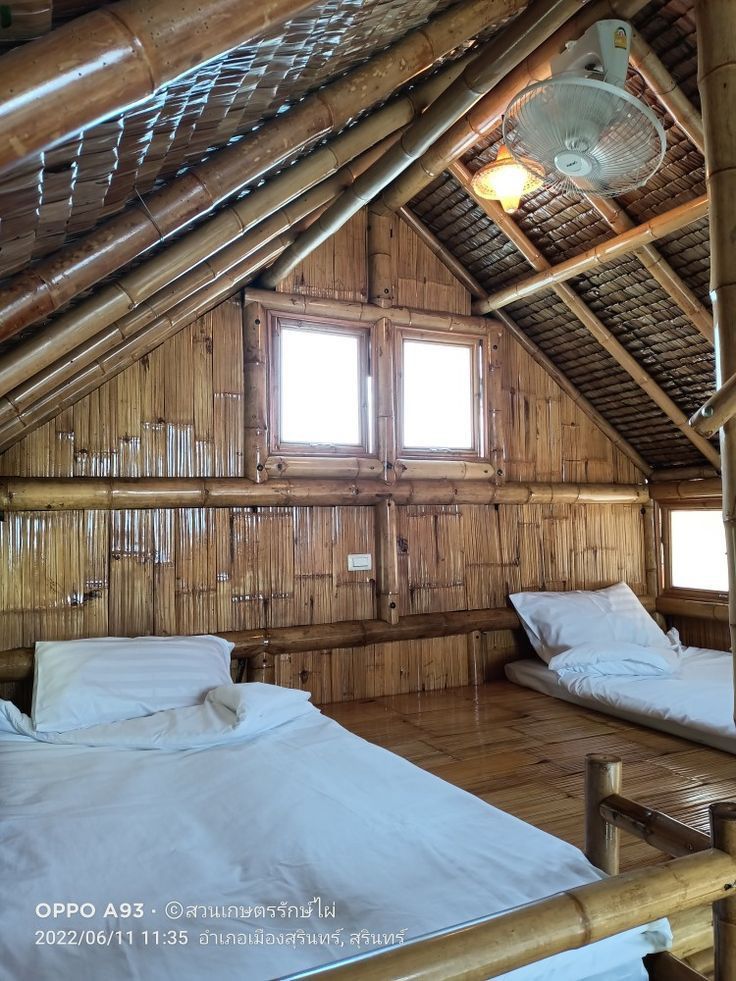 there are two beds in the room with wooden walls and flooring that is made out of bamboo