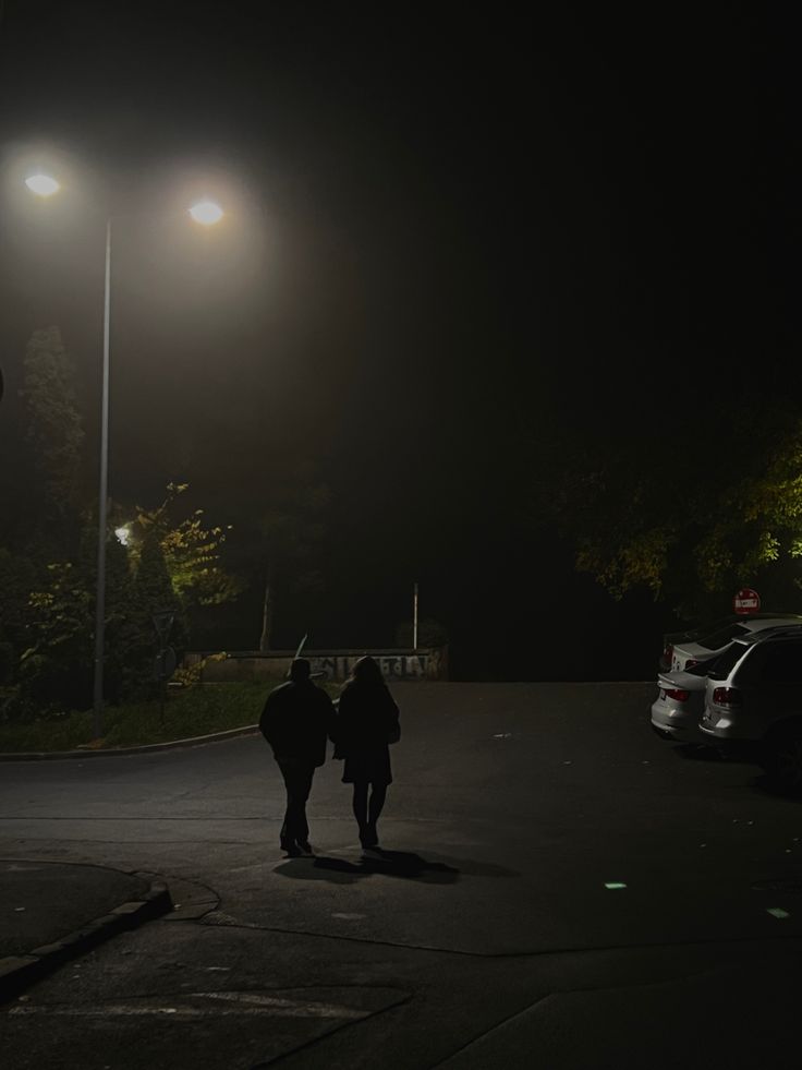 two people walking down the street at night