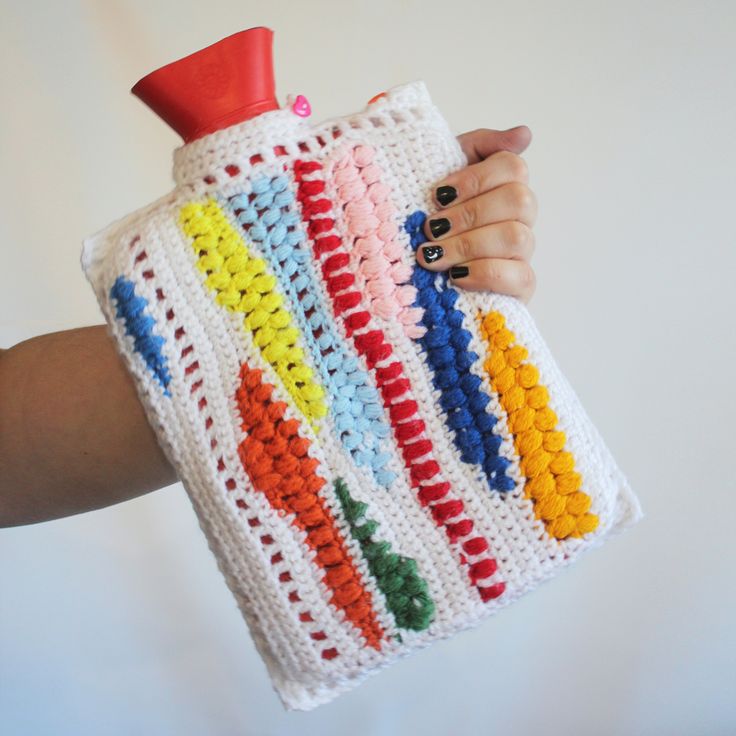 a person holding a crocheted water bottle cover in front of a white background