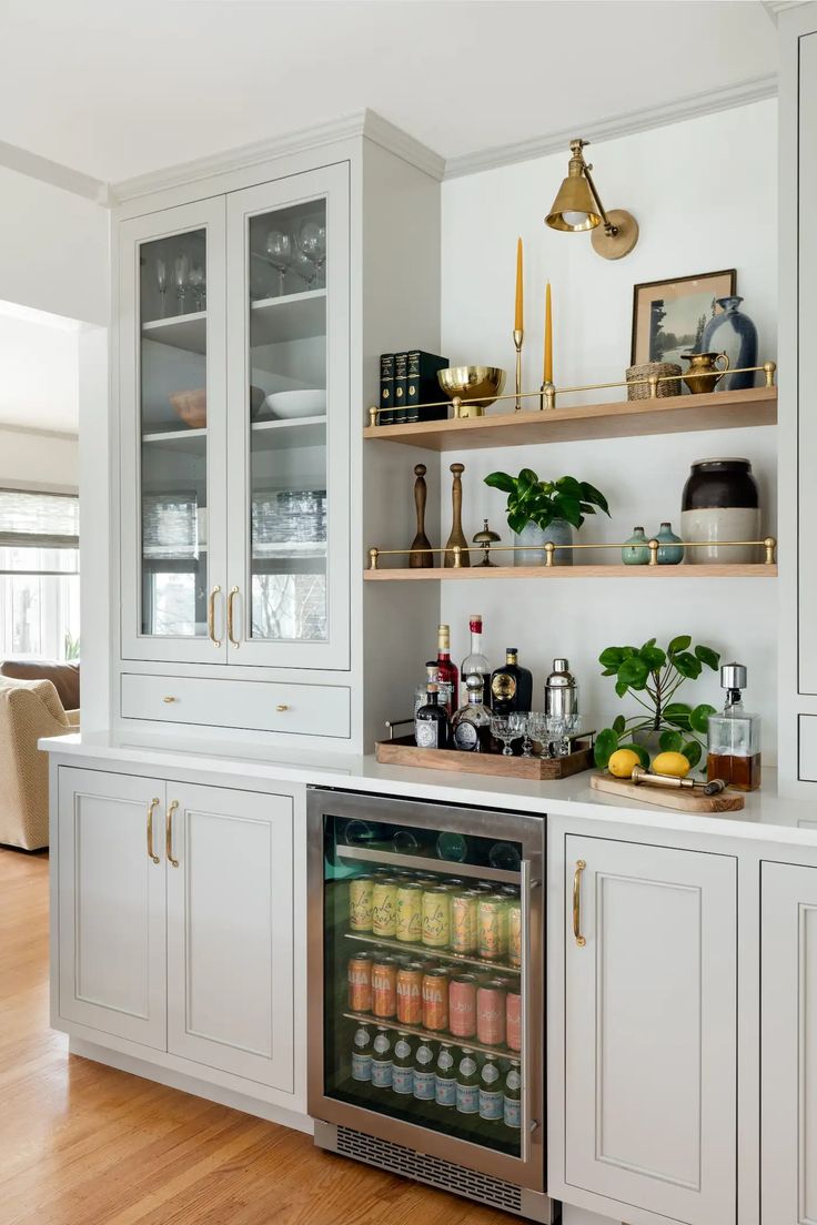 a kitchen with white cabinets and shelves filled with drinks