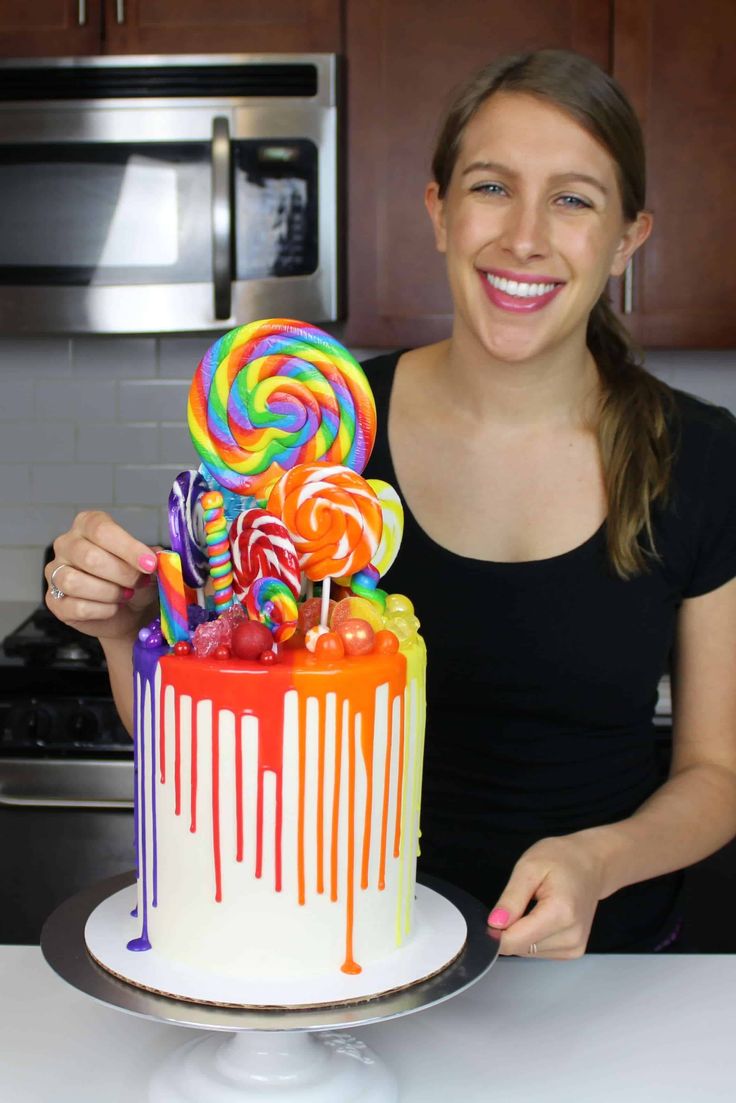 a woman is holding up a cake decorated with candy and lollipops