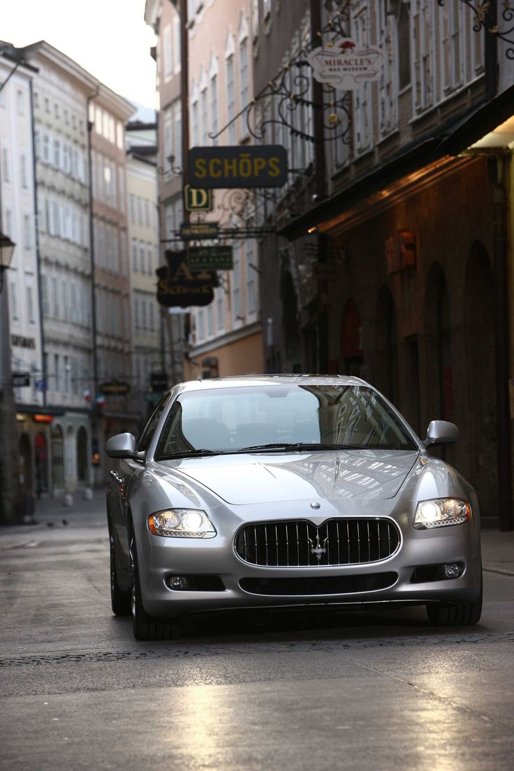 a silver car parked on the side of a street next to tall buildings and shops