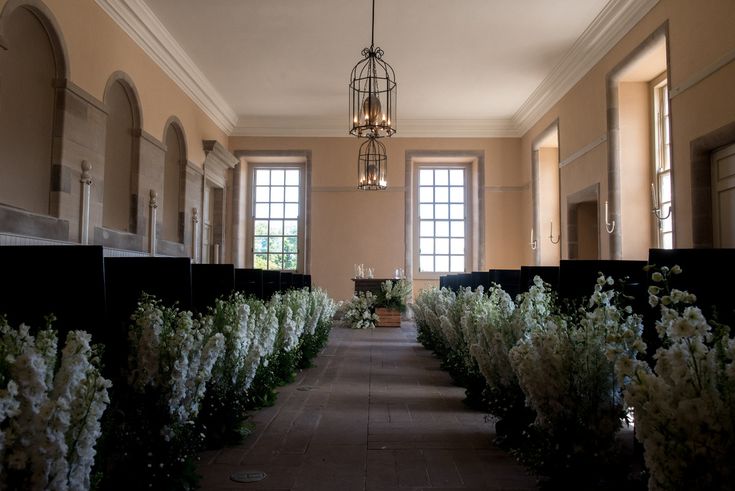 an empty church with rows of pews and flowers in the aisle between two windows