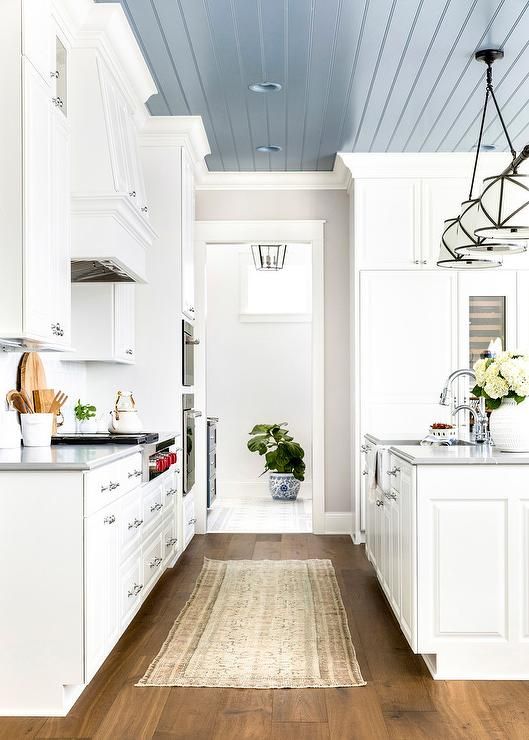 a kitchen with white cabinets and wood flooring, along with an area rug on the floor