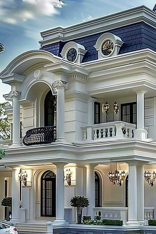 a large white house with blue roofing and balconies on the second floor